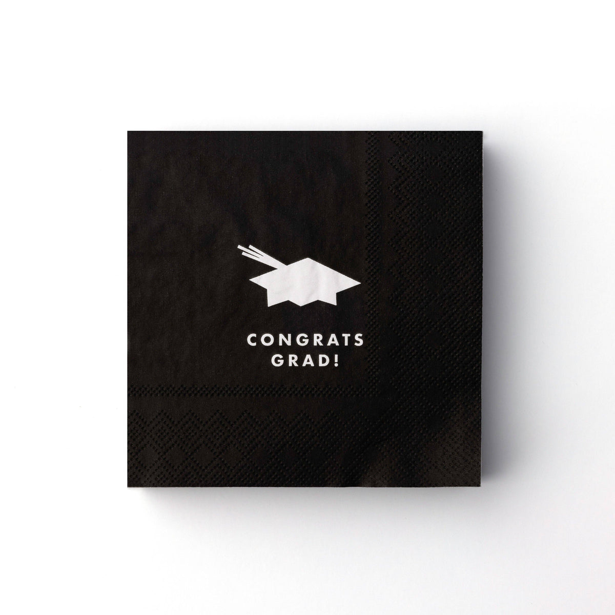 Black cocktail napkin with white graduation cap icon and “Congrats Grad” text