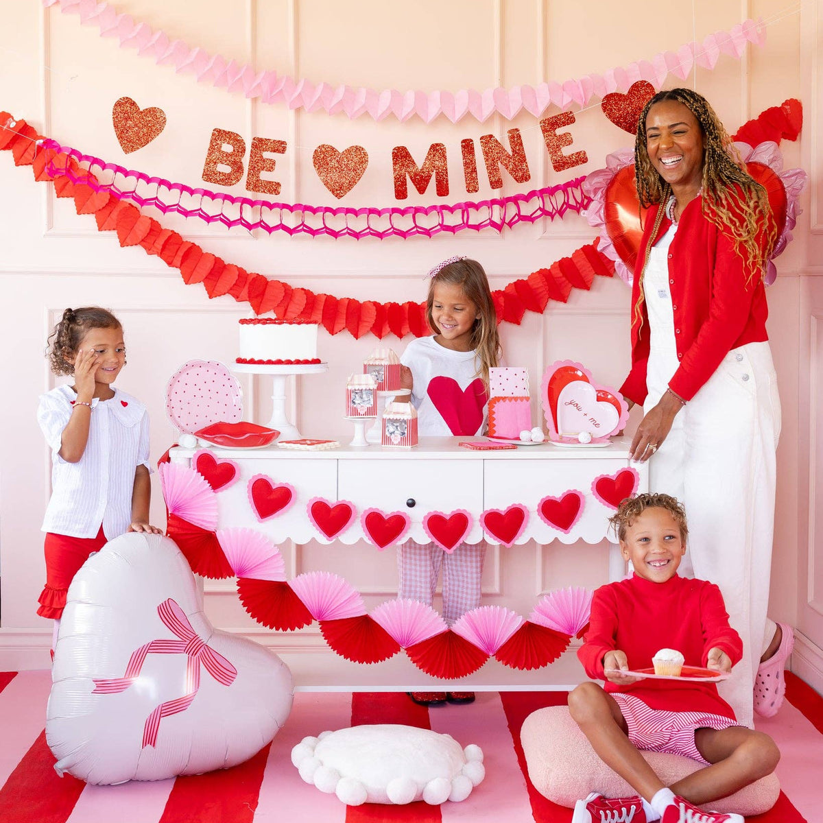 Valentine party table setup with conversation heart plates and red decor
