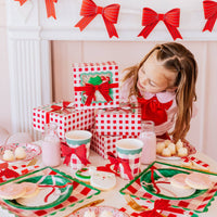 Girl setting Christmas table with red bow cookie boxes and milk bottles