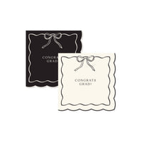 A set of black and cream Congrats Grad napkins with a scalloped edge and a Gold Foil Detail bow for a Preppy Grad celebration.