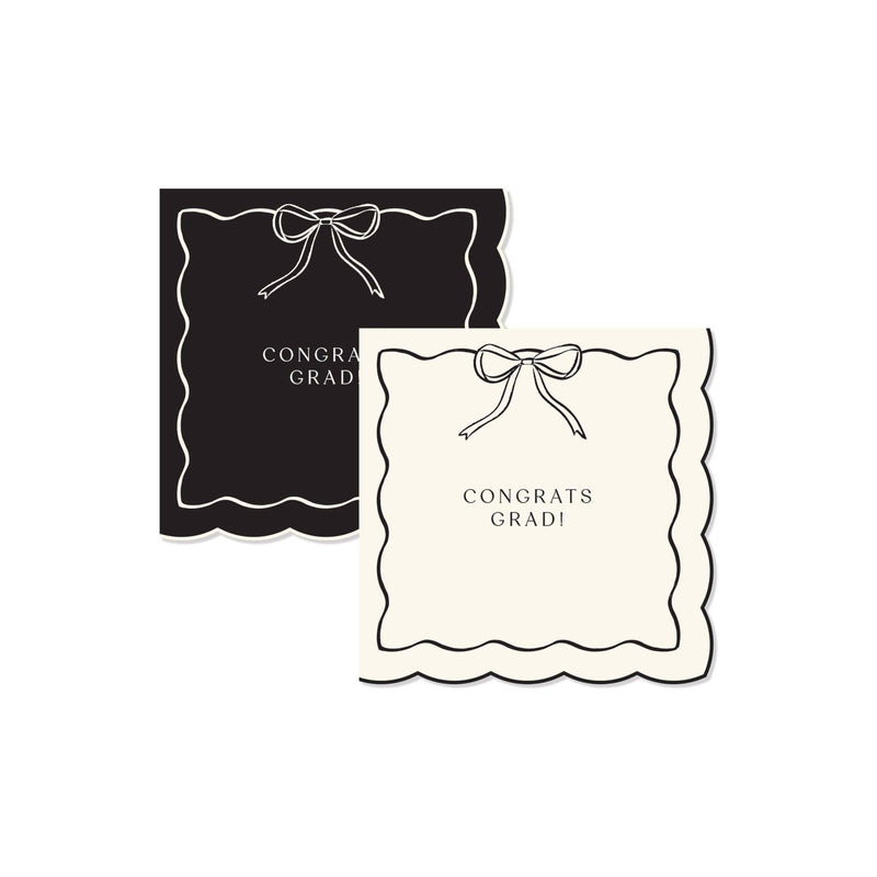 A set of black and cream Congrats Grad napkins with a scalloped edge and a Gold Foil Detail bow for a Preppy Grad celebration.