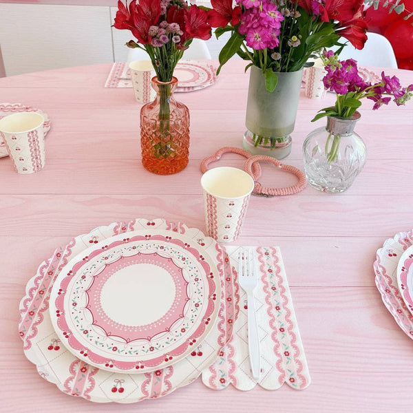 Side view of a cherry dinner plate styled on a pink table with flowers