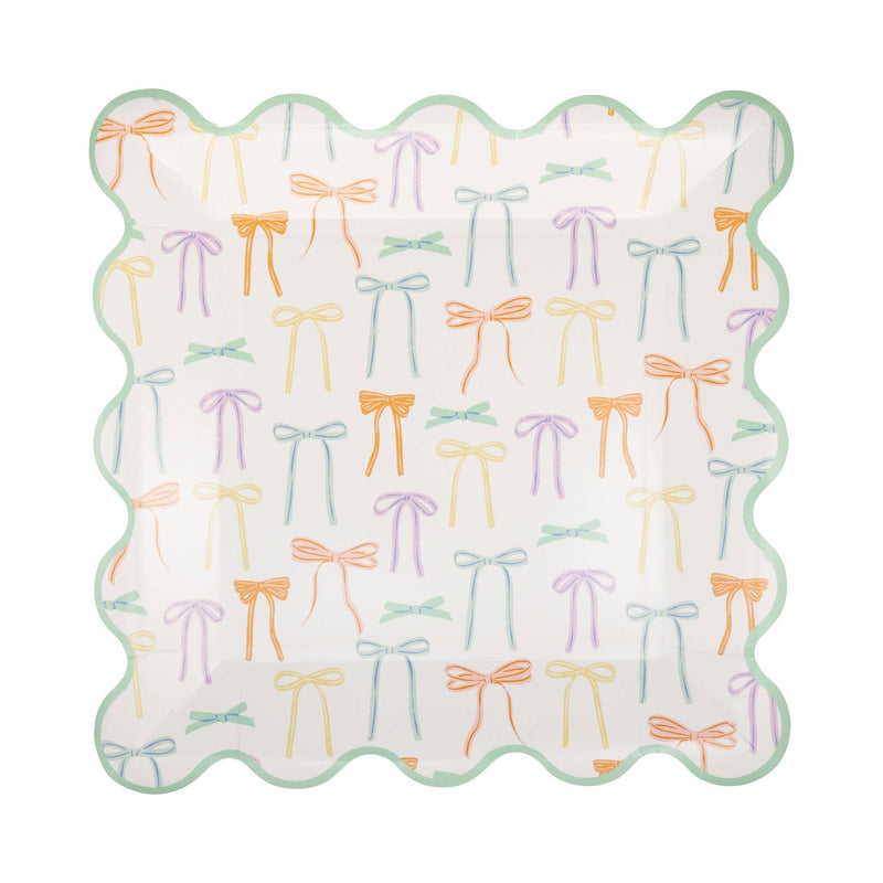 A single square paper plate with a delicate bow design in pastel colors and a green scalloped edge.