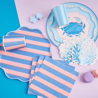 Under-the-sea table setting with blue coral shaped cocktail napkins, a crab plate, striped plates, and striped cups.
