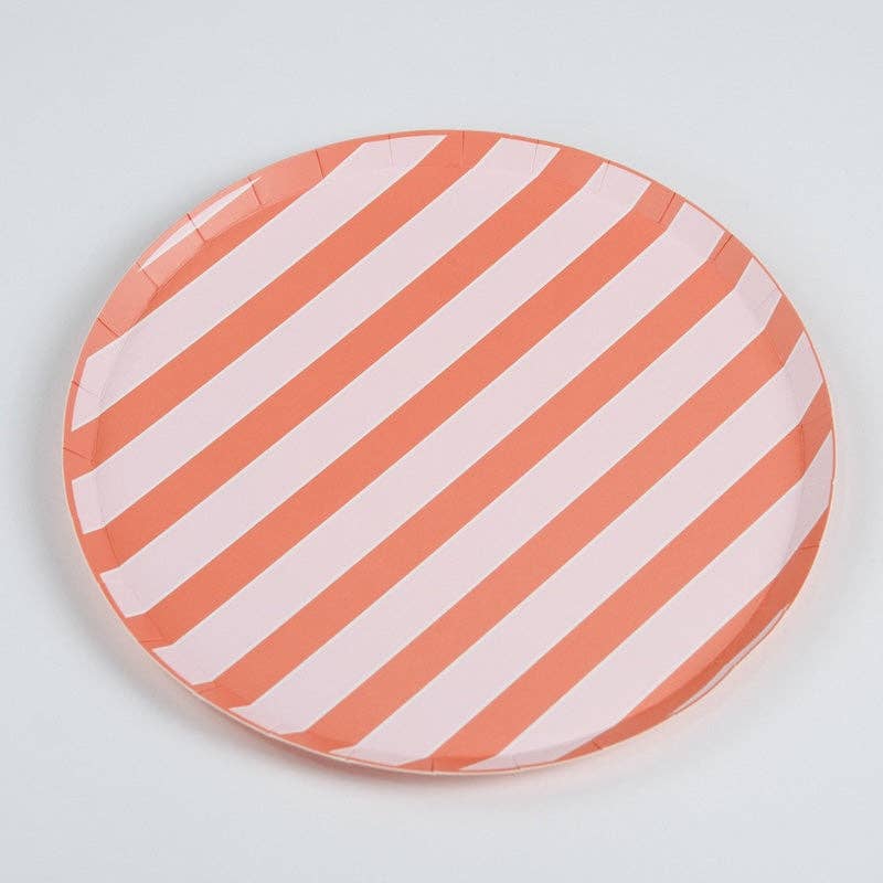 Full coral stripe dinner plate on a white surface, shot from a slightly above angle. Diagonal stripes run across the full face of the plate — approximately 8 alternating coral-orange and pale pink stripes visible. Round plate with clean edge, no scallop. Paper crimping visible at rim.