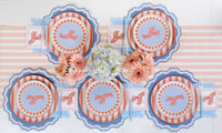 Close-up of one place setting on the blue stripe runner. Coral stripe plate stacked under the lobster salad plate with blue fork and knife resting on the salad plate. Lobster cocktail napkins on both sides. Peach gerberas and white daisies in bud vases.