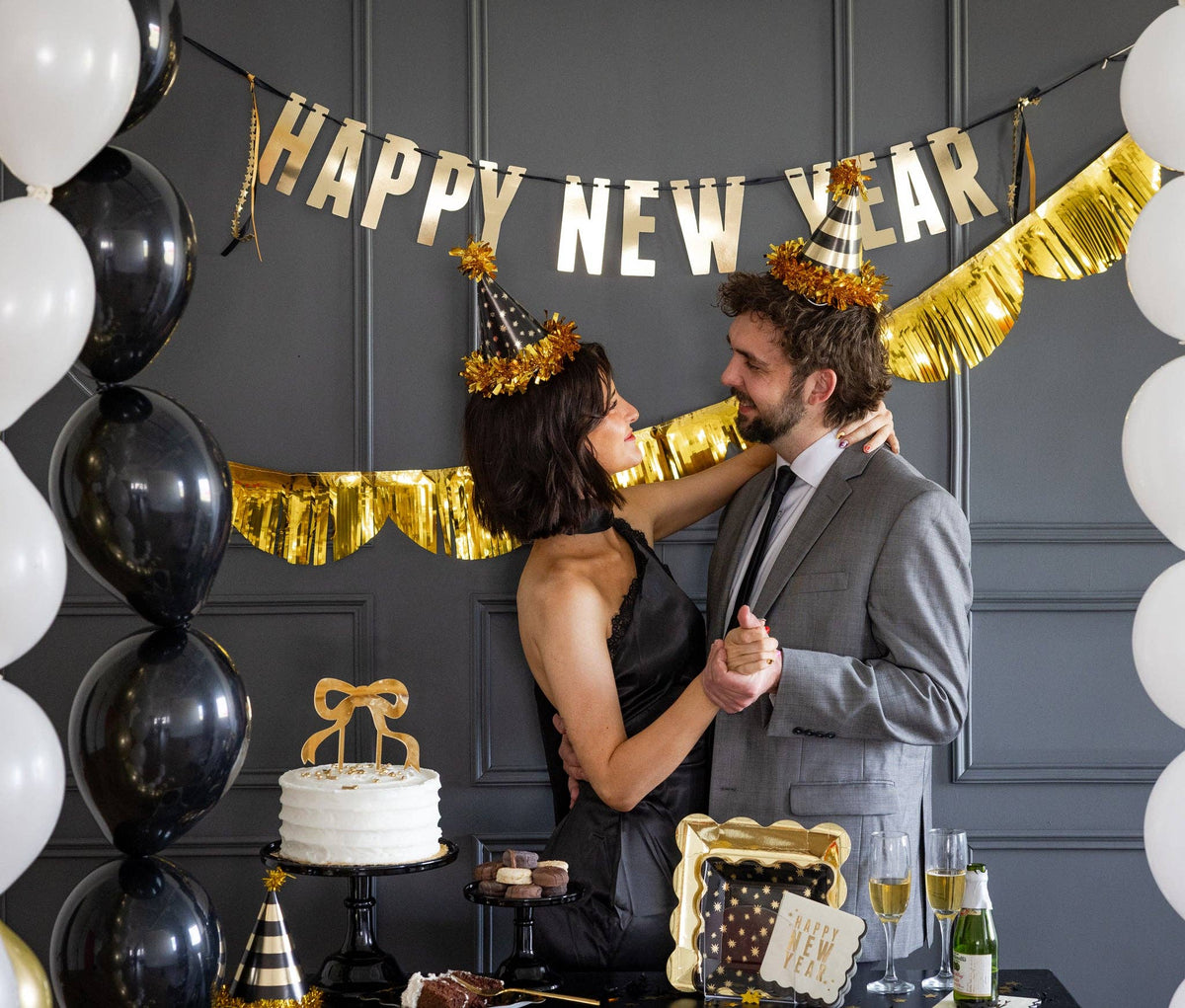 Couple wearing black and gold party hats at New Year’s celebration