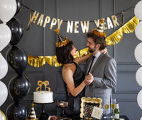 Couple wearing black and gold party hats at New Year’s celebration
