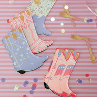 Tablescape with mixed cowgirl boot plates, confetti, and wooden forks for pink western party decorations.