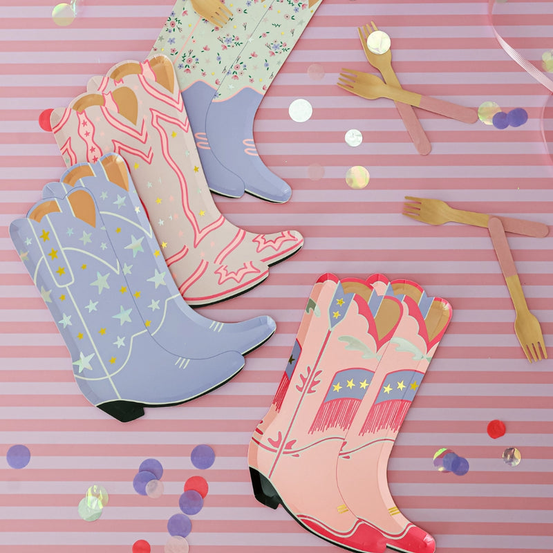 Tablescape with mixed cowgirl boot plates, confetti, and wooden forks for pink western party decorations.