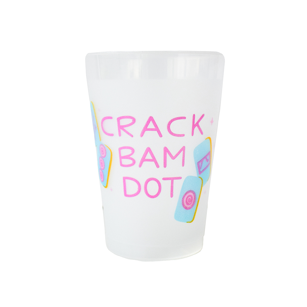 Frosted plastic mahjong party cup with "CRACK BAM DOT" printed vertically in pink lettering and scattered blue and yellow mahjong tile illustrations showing the Crak, Bam, and Dot suits, photographed on a white background