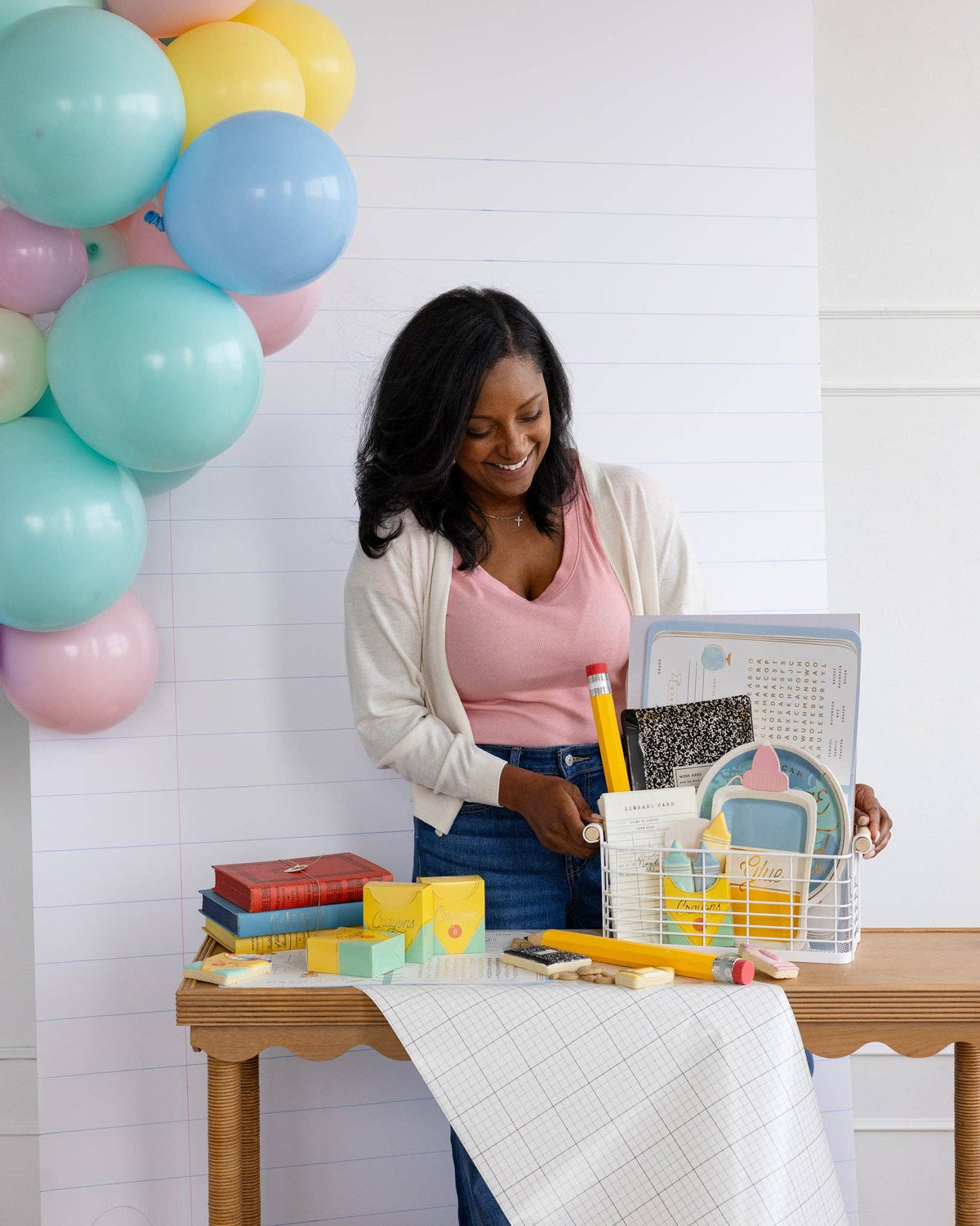 Woman looking down and smiling while arranging the wire basket. Crayon treat boxes visible left of frame, one open showing contents. Multiple versions of the box (open and closed) visible.
