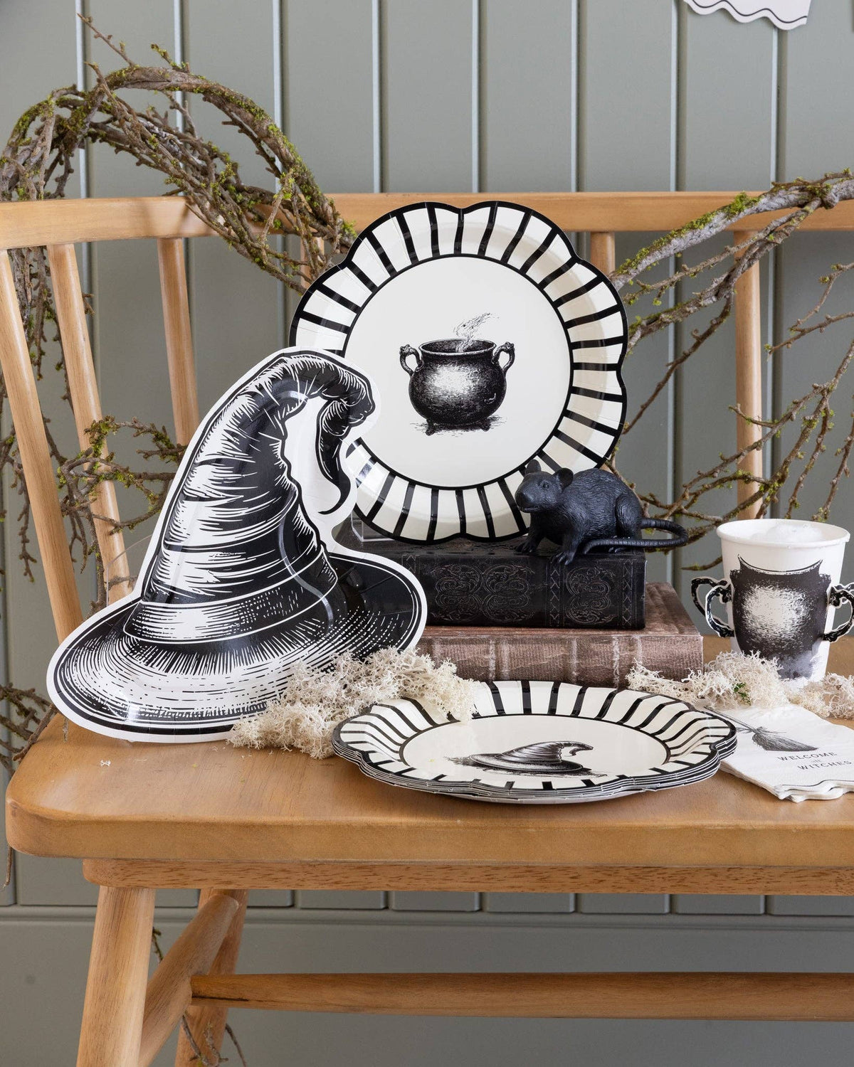 Halloween-themed table setting with halloween paper plates and a witch hat on a wooden table.