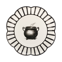 Decorative plate with black and white striped rim and central illustration of a cauldron.