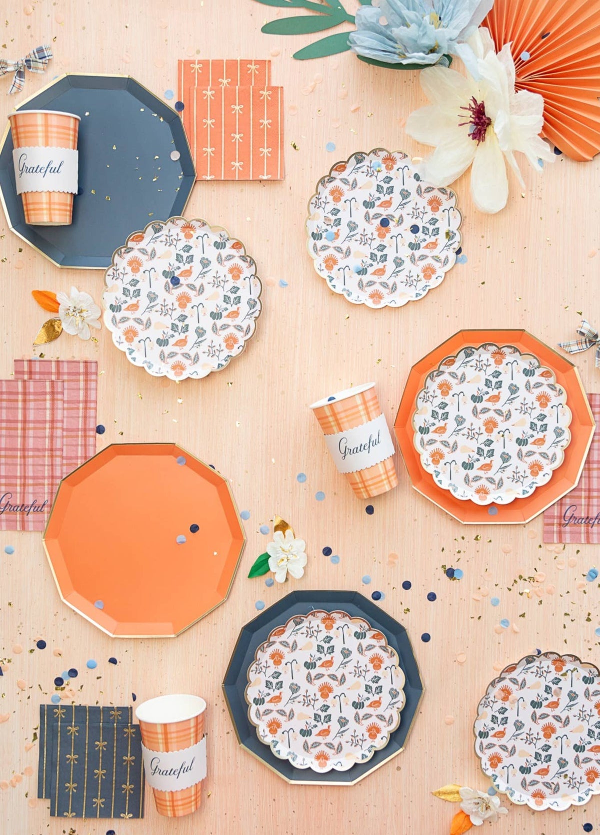 Fall table styling: Navy premium plates styled with floral dessert plates, orange plates, confetti, and plaid cups.