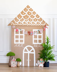 Gingerbread Banner hanging across a cardboard gingerbread house backdrop.