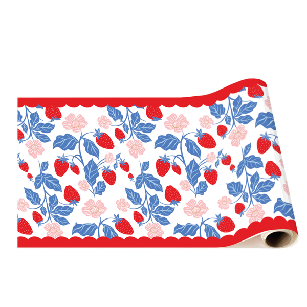 A roll of decorative table runner paper featuring a repeating pattern of red strawberries, blue leaves, and pink flowers bordered by a red scalloped edge.