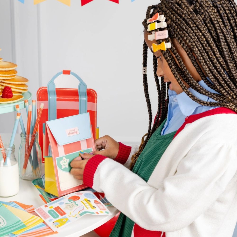 Child placing lunchbox note into bag with colorful note cards.