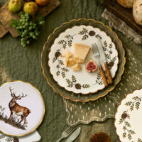 Woodland place setting with a deer plate, olive dapple-dot napkin, gold cutlery, and pinecones on an olive cloth.