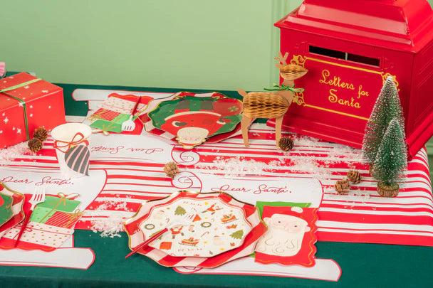 Holiday table with scroll christmas placemats, Santa plates, and gifts.