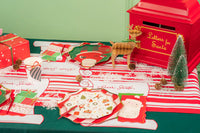 Holiday table with scroll christmas placemats, Santa plates, and gifts.