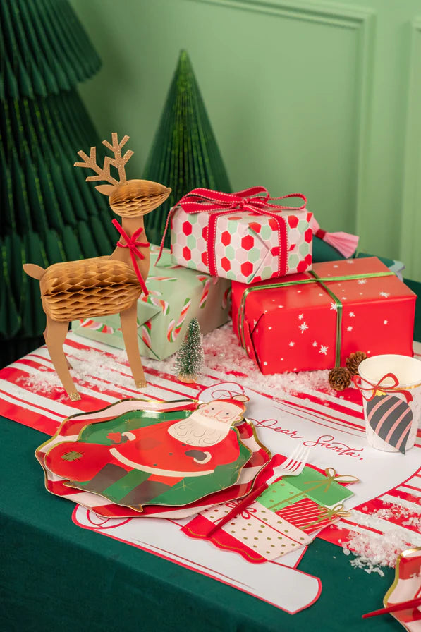 Gift table vignette with reindeer décor and scroll Christmas placemats.