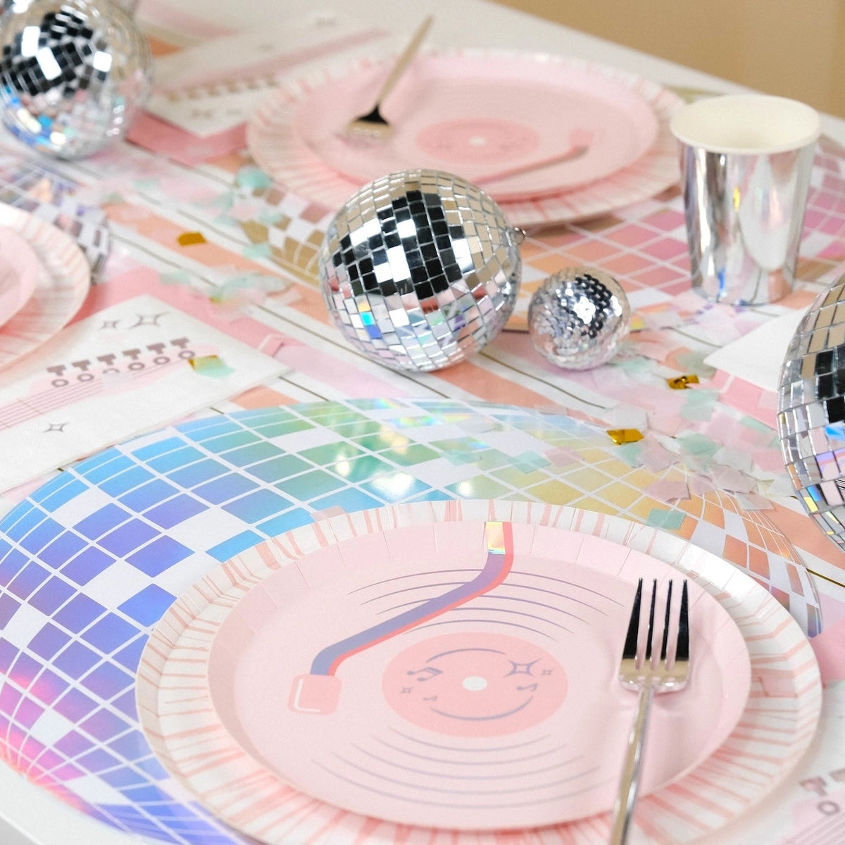 High-energy disco cowboy party table featuring holographic chargers, silver cups, and pastel confetti.
