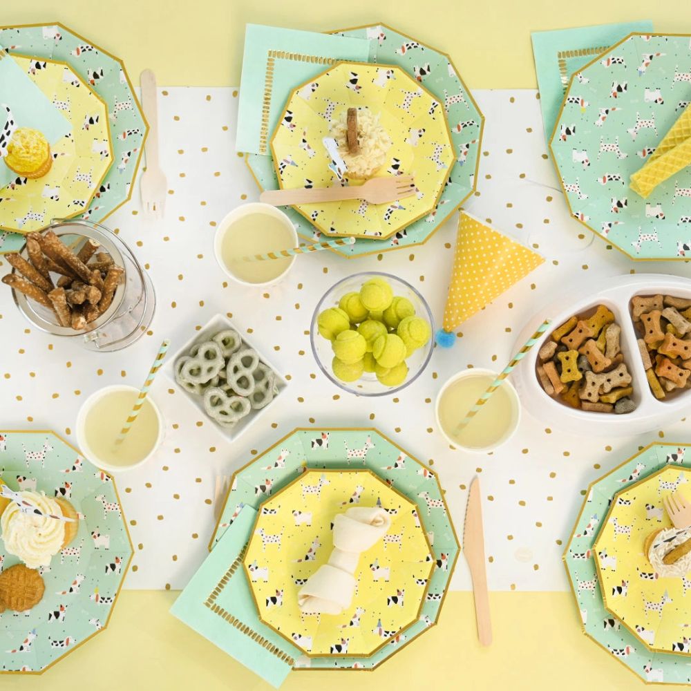 Dog birthday party table styled with yellow and mint plates and snacks