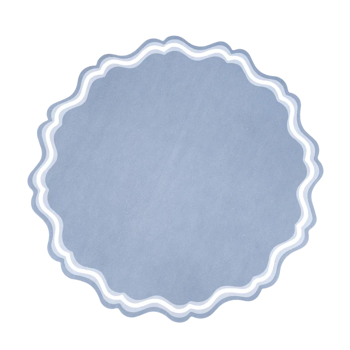 Single dusty blue round scalloped paper placemat on white background, straight-on view. Full silhouette shows the large-scale scalloped edge (approximately 20–22 scallop points) and the two concentric wave border lines in white and light blue against the slate blue body.