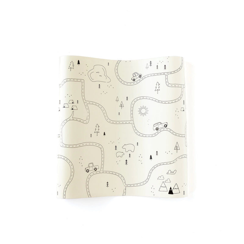 Flat view of the Adventure Paper Table Runner featuring a hand-drawn forest map with winding roads, tents, trees, bears, and sun illustrations.