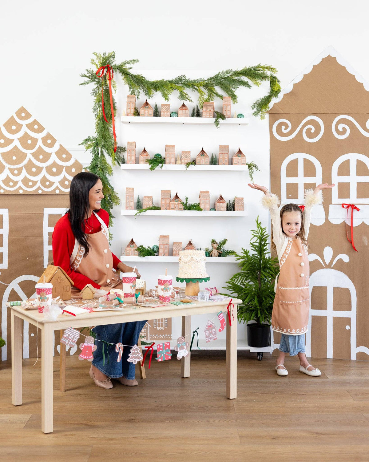 Woman and child in a festive setting with gingerbread house decorations and a Christmas tree.