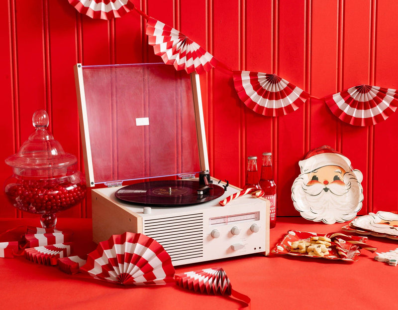 Retro holiday party setup with record player, red and white fan bunting banner, and vintage Santa tableware.
