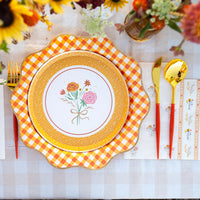 Close place setting: floral salad plate layered on top of the gingham dinner plate with gold cutlery.