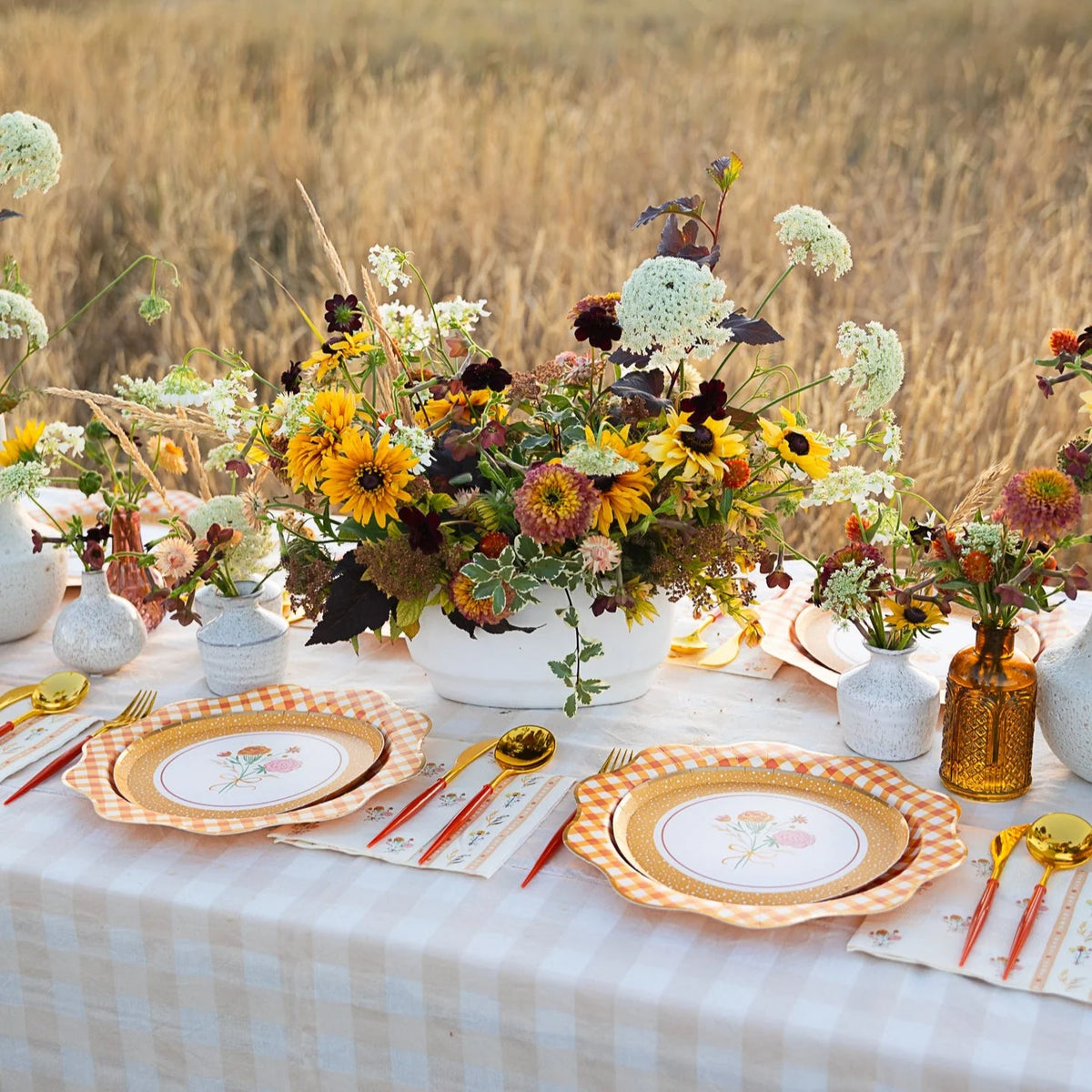 Outdoor fall table featuring wildflower arrangements and orange-gingham dinner plates.