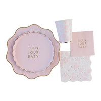 Flat‑lay of coordinating Bonjour Baby party set showing scalloped plates, floral cup and Emma Bear napkins.
