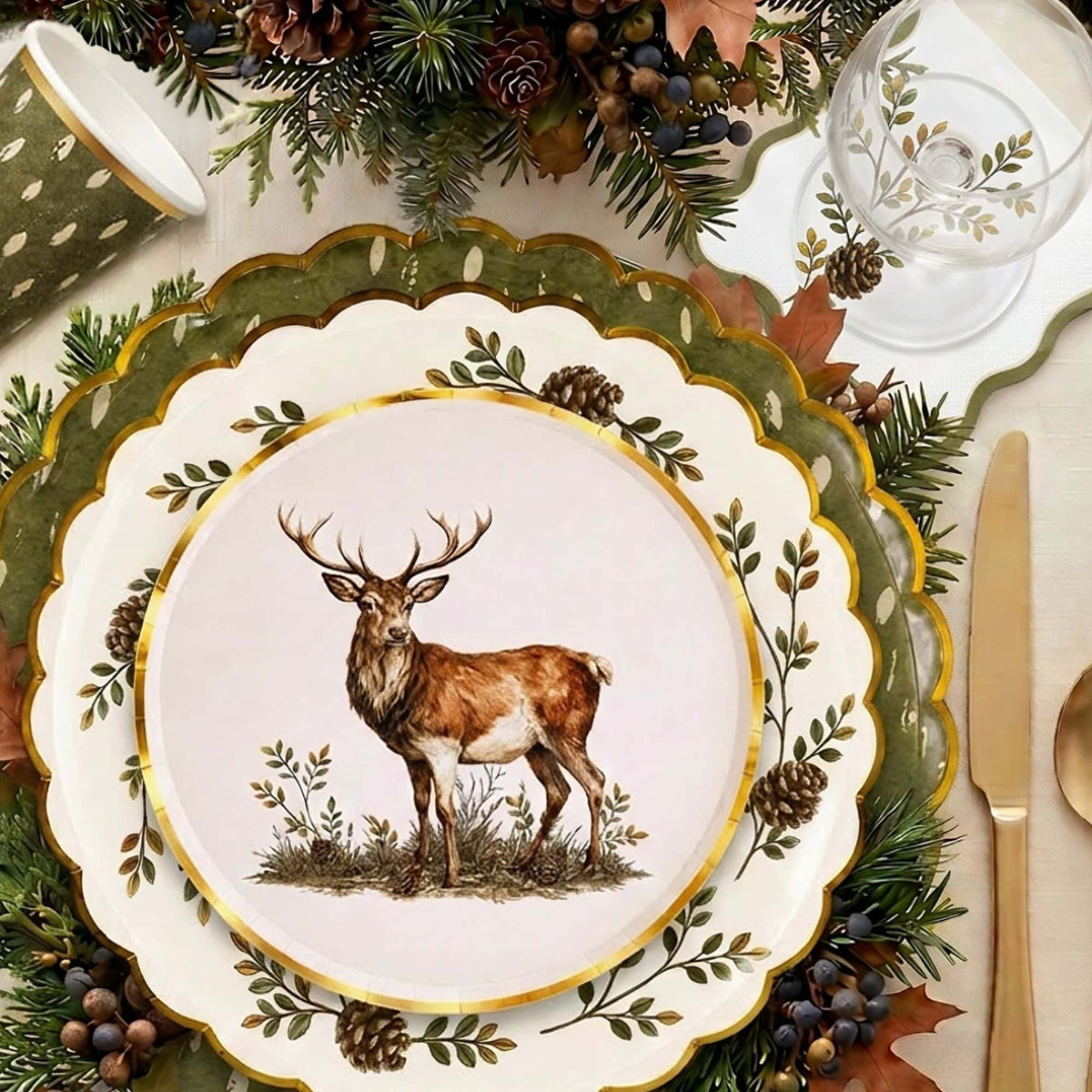 Woodland place setting with a stag plate on a pinecone plate and olive charger, gold cutlery, pinecones, and the cocktail napkin.