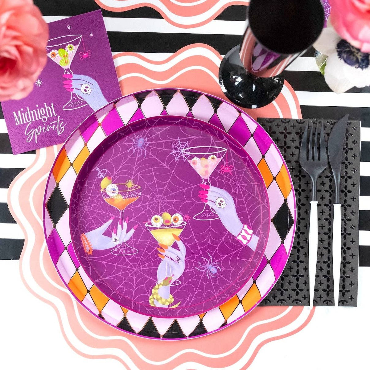 Layered Halloween place setting showing the Midnight Spirits plate on a striped table runner next to black plastic cutlery and a pink scalloped napkin.