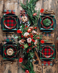 Overhead view of Christmas table with plaid plates and floral centerpiece