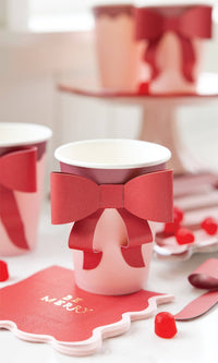Close-up of pink and burgundy cup with bow surrounded by red holiday candies