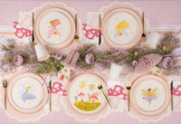 Overhead tablescape with fairy plates, gold flatware, and mushroom napkins.