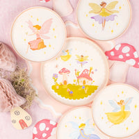 Set of coordinating fairy plates on pink table with mushroom décor.