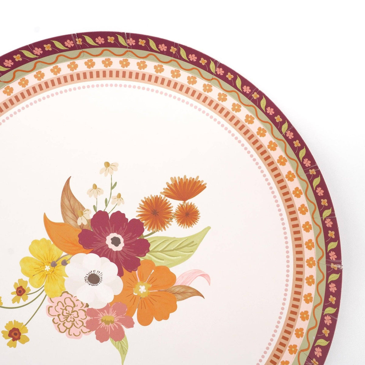 Overhead of a single fall floral dessert plate showing the bouquet and patterned border on the neutral base.