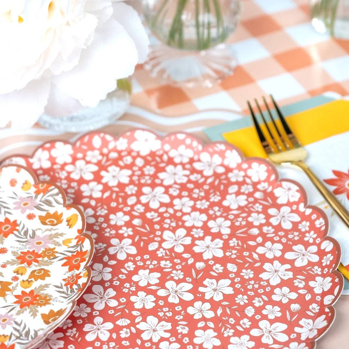 Close view of the rust floral scalloped plate beside the cream retro floral design