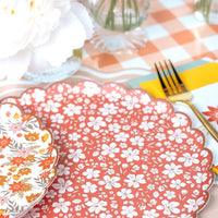 Close view of the rust floral scalloped plate beside the cream retro floral design