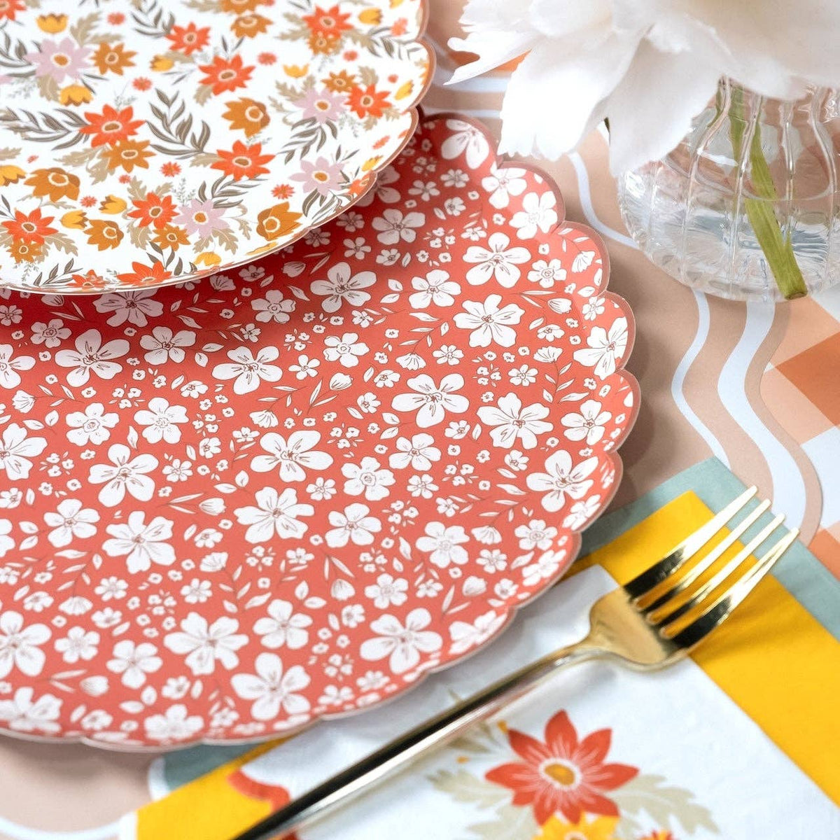 Both fall floral plate designs on a peach gingham table with white peonies and bud vases
