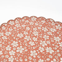 Detail of the scalloped rim and cream floral pattern on a terracotta paper plate