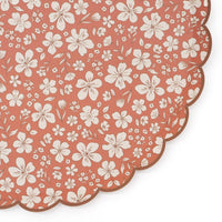 Close crop of the scalloped edge and cream flower print on the rust paper dinner plate