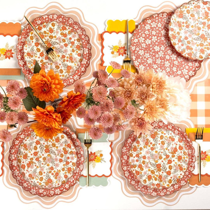 Overhead fall tablescape with both floral plate designs layered on a peach gingham runner with dahlias