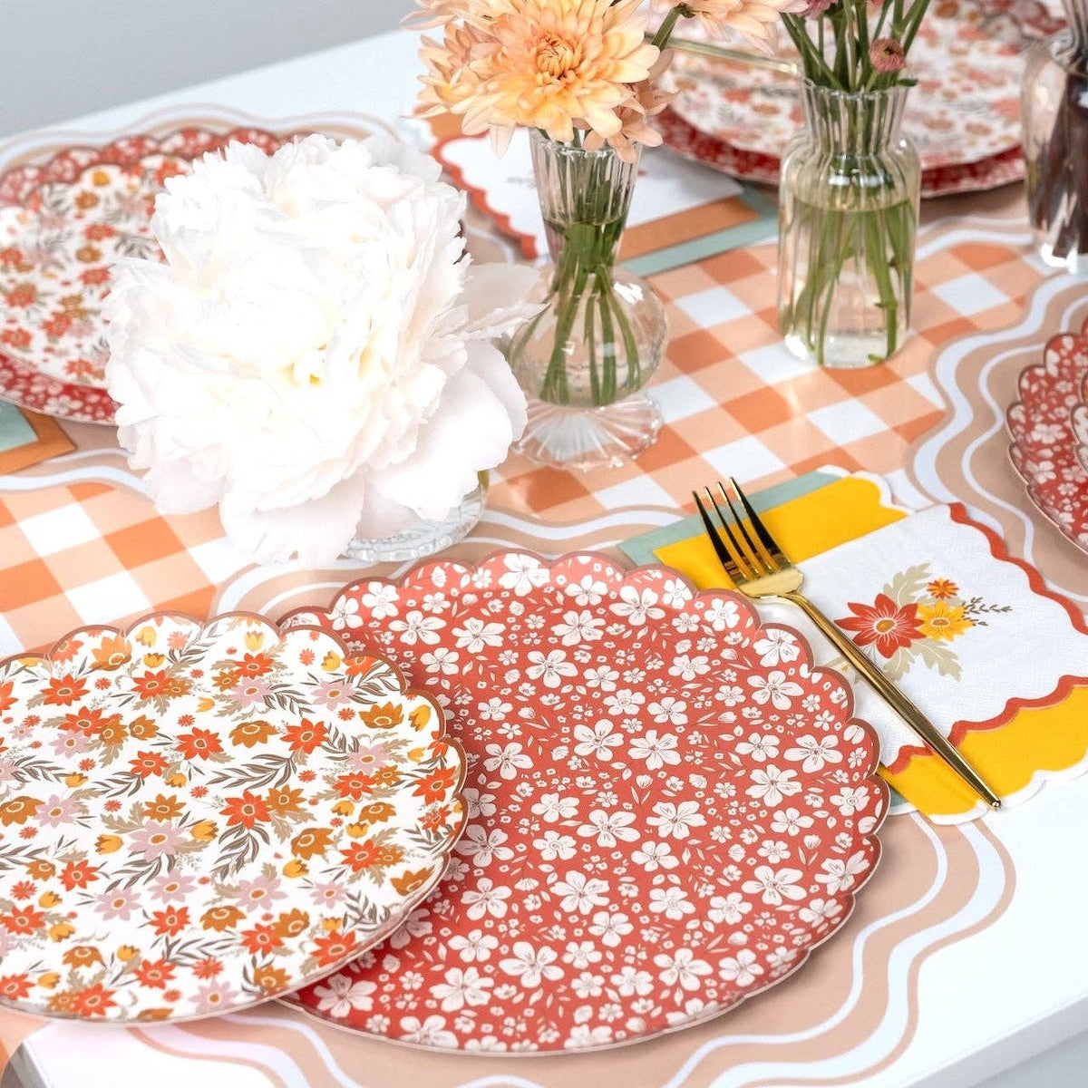 Close view of the rust floral scalloped plate beside the cream retro floral design