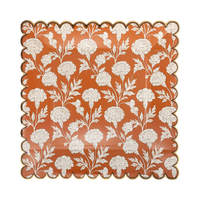 Orange square paper plate with cream florals and a copper foil scalloped edge, front view.